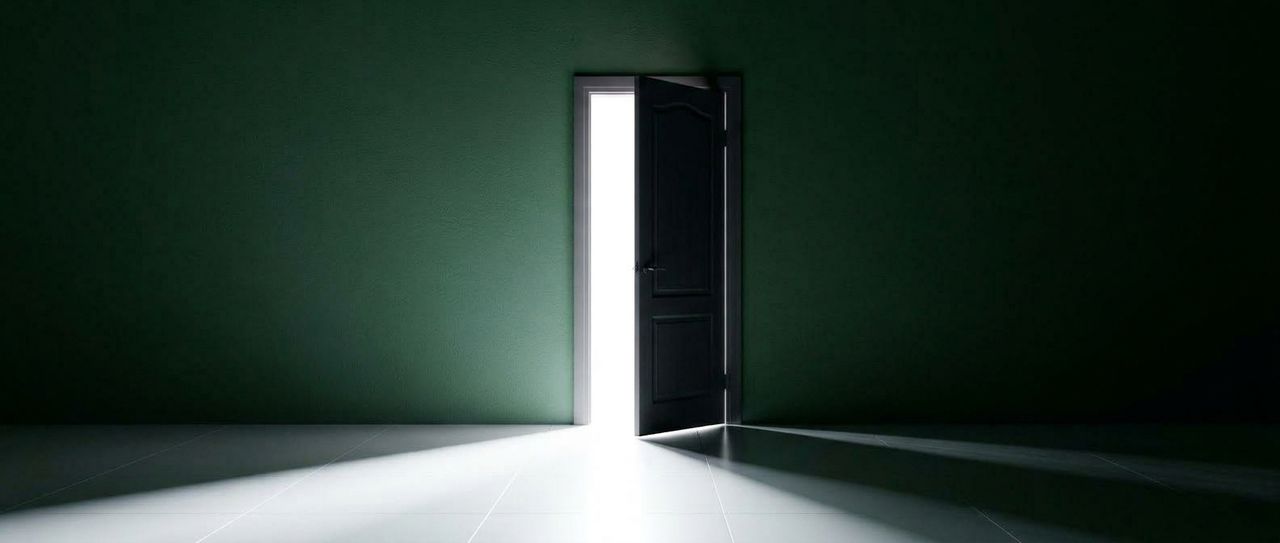Puerta entreabierta en una habitación oscura con un haz de luz blanca